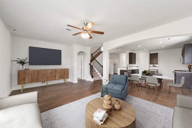 living room featuring dark hardwood / wood-style flooring, ceiling fan, and sink