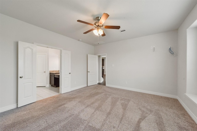 unfurnished bedroom featuring ceiling fan, light carpet, and ensuite bath