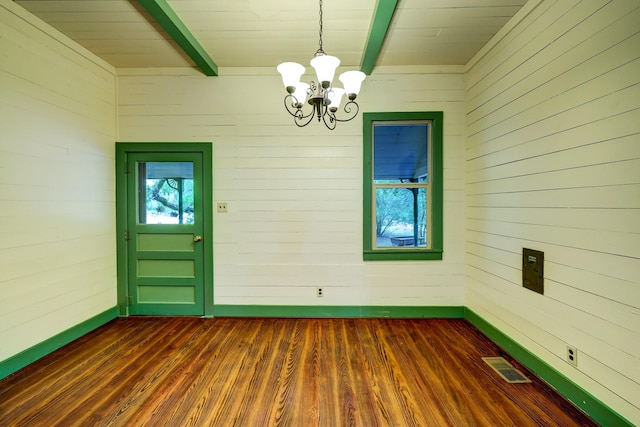 interior space with wooden walls, beamed ceiling, a chandelier, and dark hardwood / wood-style floors