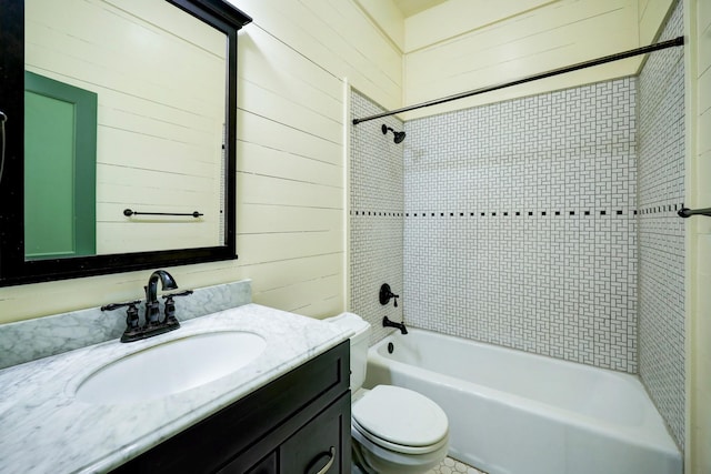 full bathroom featuring vanity, toilet, tiled shower / bath combo, and wood walls