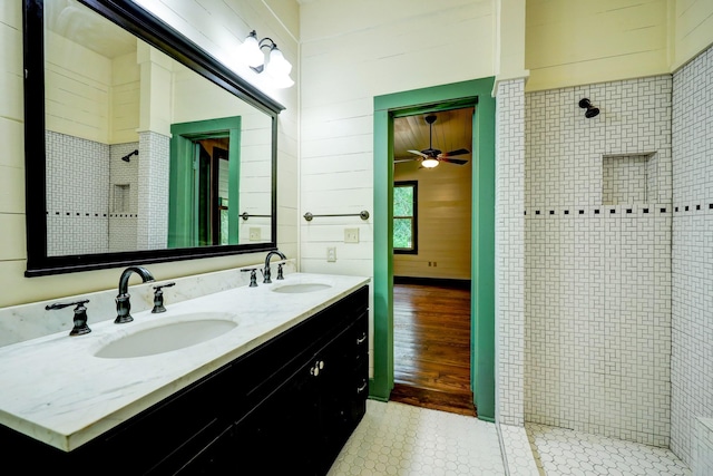 bathroom featuring vanity, a tile shower, and wood-type flooring