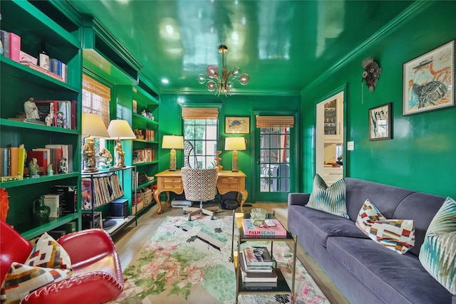 living area with wood-type flooring, ornamental molding, and an inviting chandelier