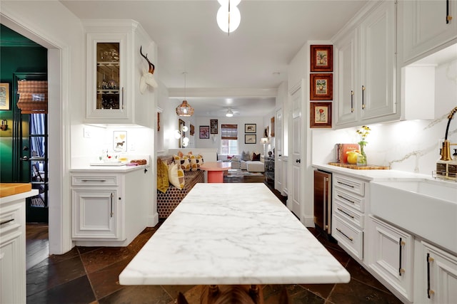 kitchen featuring pendant lighting, a kitchen island, white cabinets, and beverage cooler