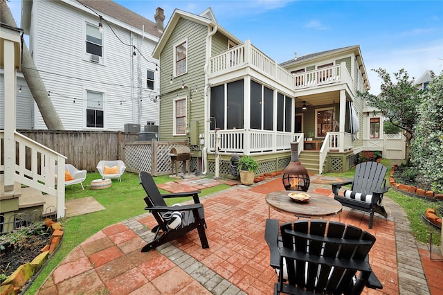 back of house featuring a sunroom, a fire pit, central AC, a balcony, and a patio