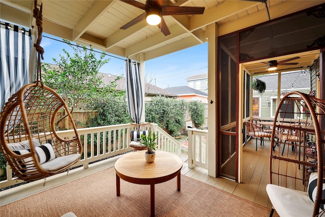 sunroom / solarium featuring beamed ceiling, ceiling fan, and a healthy amount of sunlight