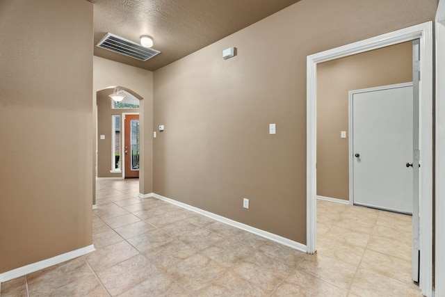 hallway with light tile patterned floors and a textured ceiling