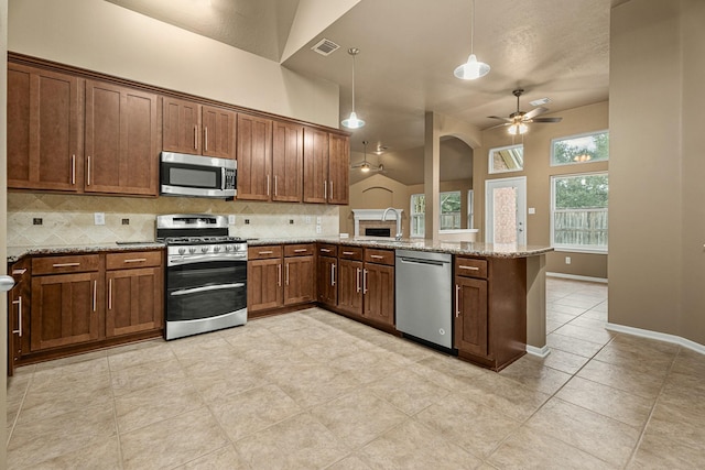 kitchen with kitchen peninsula, appliances with stainless steel finishes, vaulted ceiling, ceiling fan, and hanging light fixtures