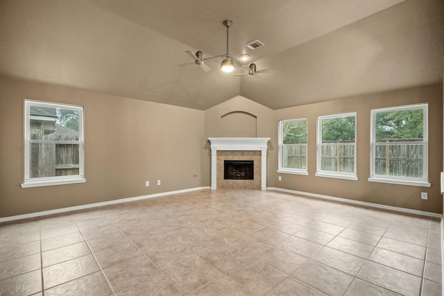 unfurnished living room featuring a wealth of natural light, ceiling fan, light tile patterned floors, and a tiled fireplace