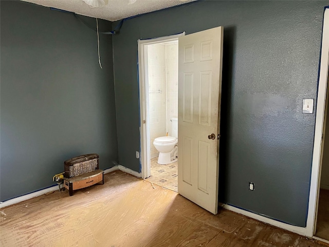 unfurnished bedroom with wood-type flooring and ensuite bath