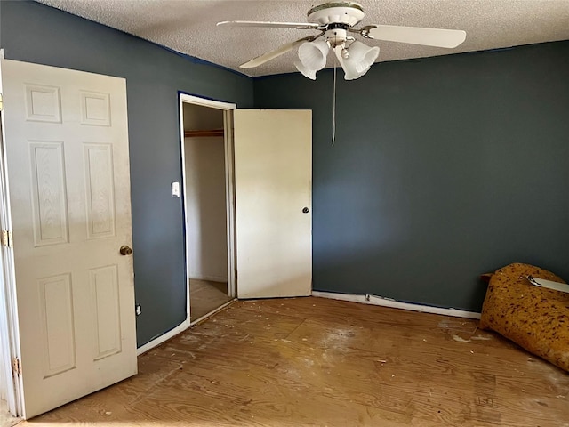 unfurnished bedroom featuring wood-type flooring, a textured ceiling, a closet, and ceiling fan