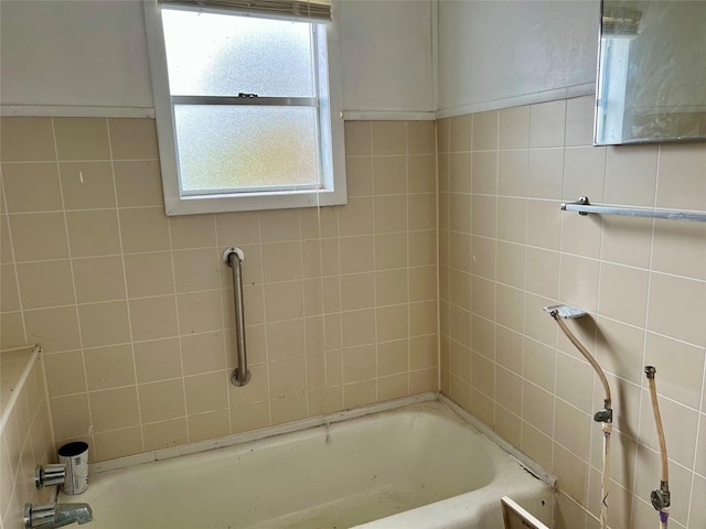 bathroom with plenty of natural light, a bath, and tile walls