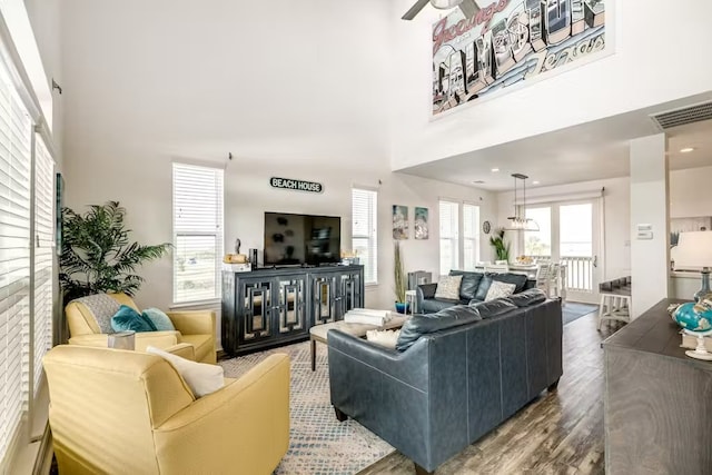 living area with a towering ceiling, wood finished floors, and visible vents