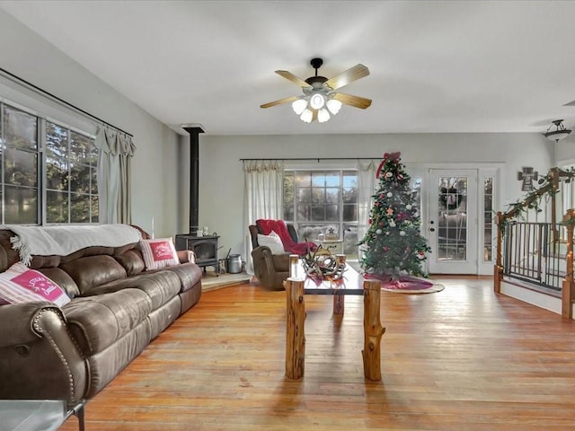 living room featuring ceiling fan, light hardwood / wood-style floors, and a wood stove