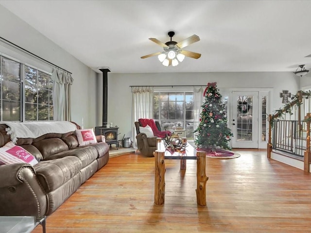 living room with light hardwood / wood-style floors, a wood stove, and ceiling fan