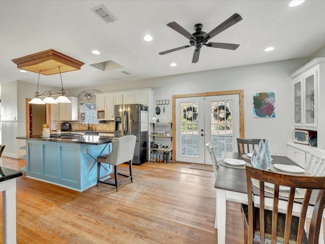 kitchen with white cabinetry, stainless steel fridge, decorative light fixtures, and light wood-type flooring