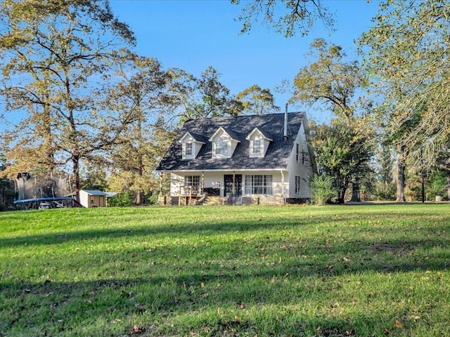 cape cod home with a front lawn, a storage unit, and a trampoline