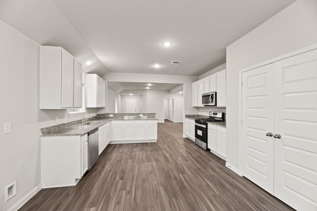 kitchen featuring light stone countertops, appliances with stainless steel finishes, sink, dark hardwood / wood-style floors, and white cabinetry