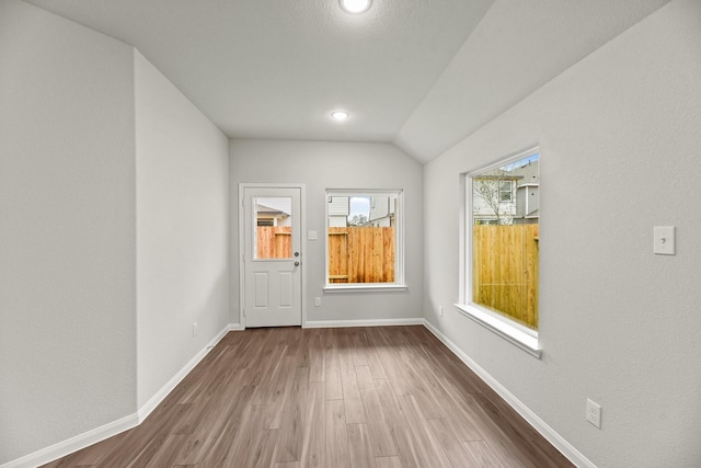 unfurnished room featuring hardwood / wood-style floors and vaulted ceiling