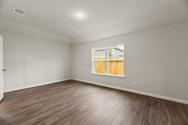 spare room featuring lofted ceiling and dark wood-type flooring