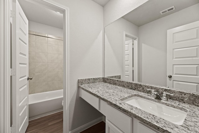 bathroom featuring vanity, wood-type flooring, and tiled shower / bath combo