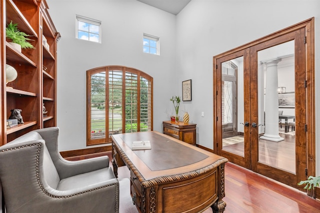 office area featuring french doors, a towering ceiling, and wood-type flooring