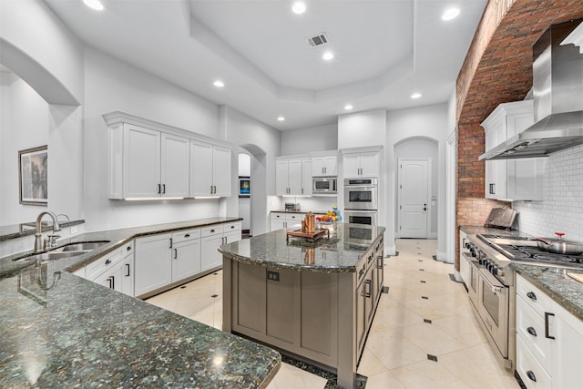 kitchen with white cabinetry, wall chimney exhaust hood, stainless steel appliances, and a large island