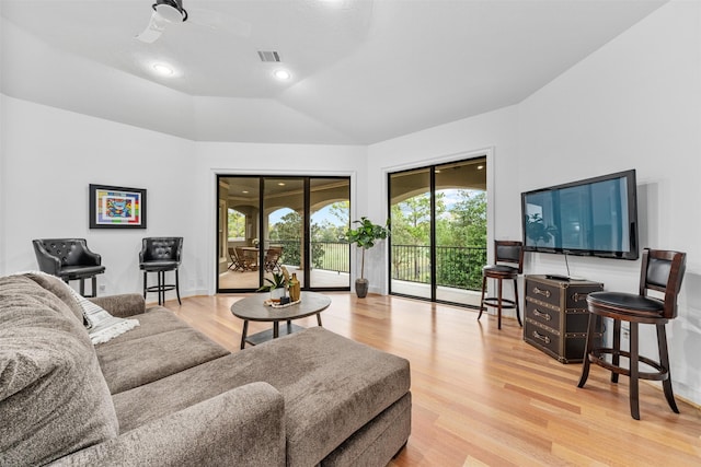 living room with ceiling fan, light wood-type flooring, and lofted ceiling