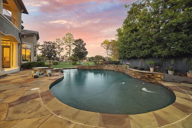 pool at dusk featuring a patio area