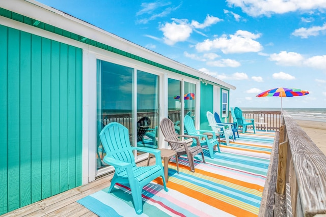 wooden deck with a water view and a beach view