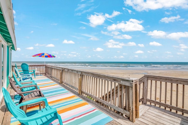 wooden terrace featuring a water view and a view of the beach