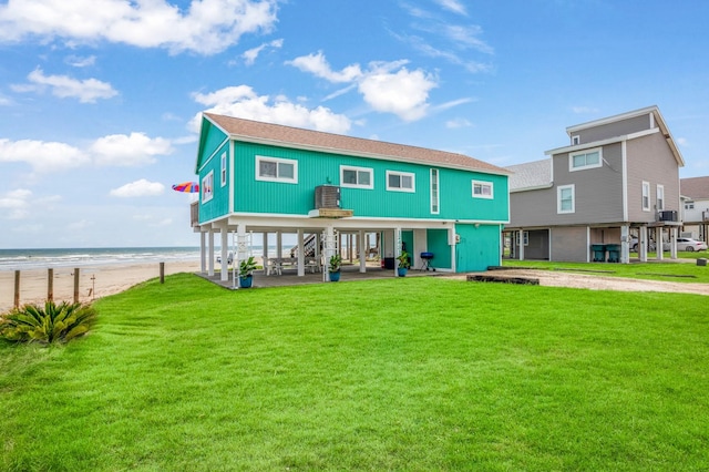 rear view of property with a view of the beach, a lawn, and a water view