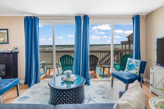 living area featuring a water view, wood finished floors, and baseboards