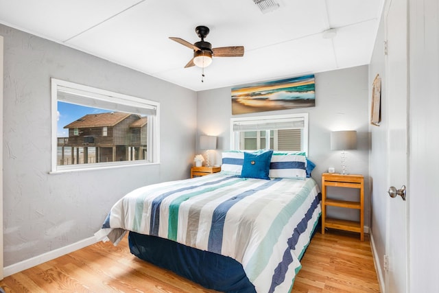 bedroom with light wood finished floors, baseboards, visible vents, and ceiling fan