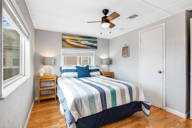 bedroom with light wood-style floors, baseboards, visible vents, and ceiling fan