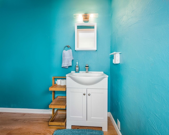 bathroom with wood finished floors, vanity, and baseboards