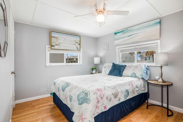 bedroom featuring hardwood / wood-style flooring, ceiling fan, and multiple windows