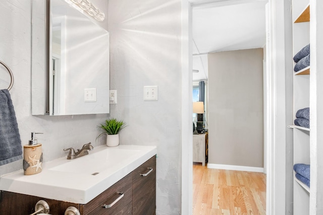 bathroom featuring baseboards, wood finished floors, and vanity