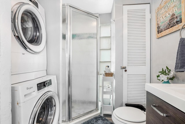 bathroom featuring walk in shower, stacked washer and dryer, vanity, and toilet