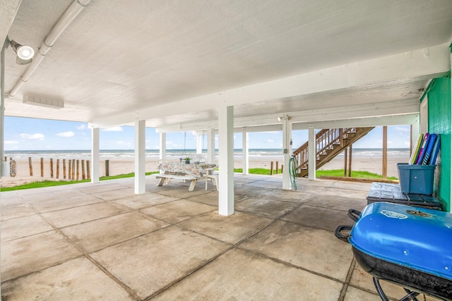 view of patio / terrace with a water view, a beach view, area for grilling, and stairs