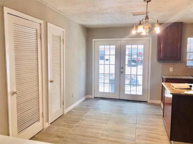 doorway with an inviting chandelier, light tile patterned floors, a textured ceiling, and french doors