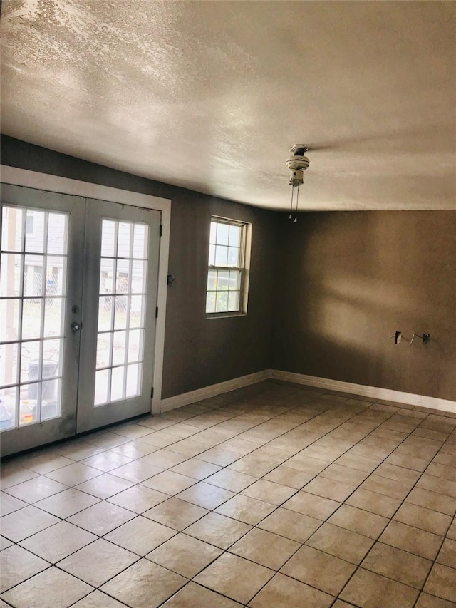 tiled spare room featuring french doors and a textured ceiling