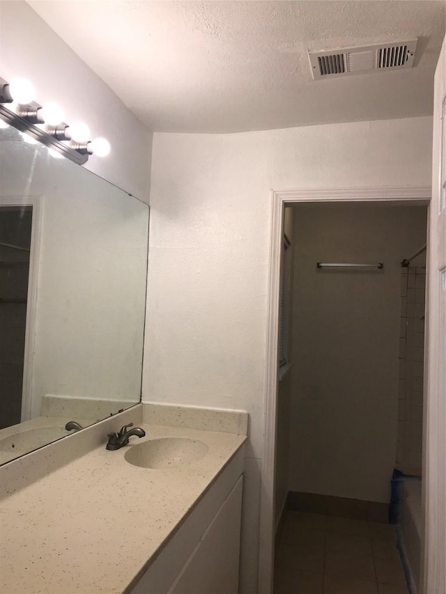 bathroom featuring tile patterned flooring, vanity, and a textured ceiling