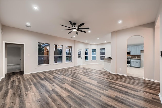 unfurnished living room with ceiling fan and dark wood-type flooring