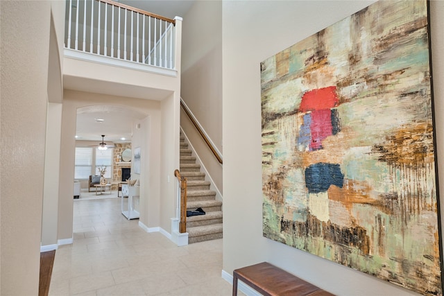 entrance foyer with a stone fireplace, light tile patterned floors, and a high ceiling