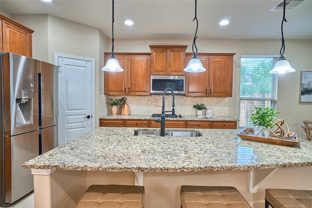 kitchen featuring pendant lighting, a breakfast bar, backsplash, light stone countertops, and stainless steel appliances