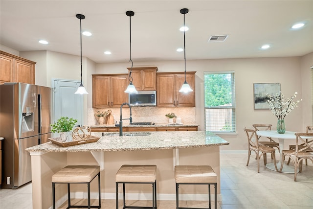 kitchen with a center island with sink, decorative light fixtures, and appliances with stainless steel finishes