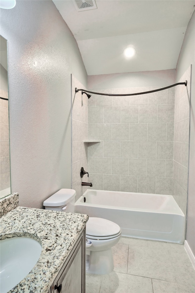 full bathroom with tiled shower / bath combo, tile patterned floors, lofted ceiling, toilet, and vanity