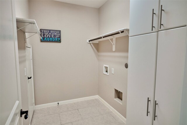 laundry area with hookup for a washing machine, light tile patterned flooring, and cabinets