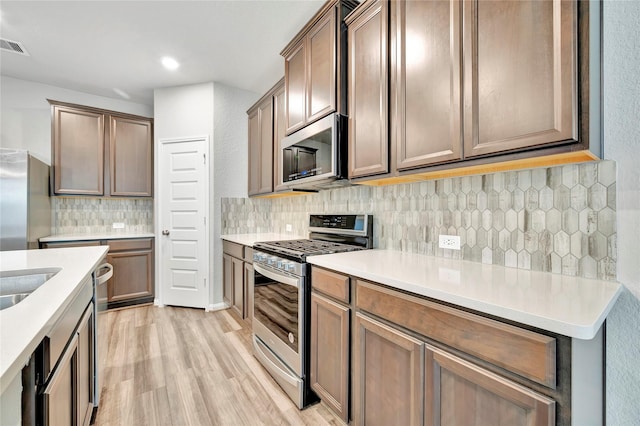 kitchen featuring backsplash, stainless steel appliances, and light hardwood / wood-style floors