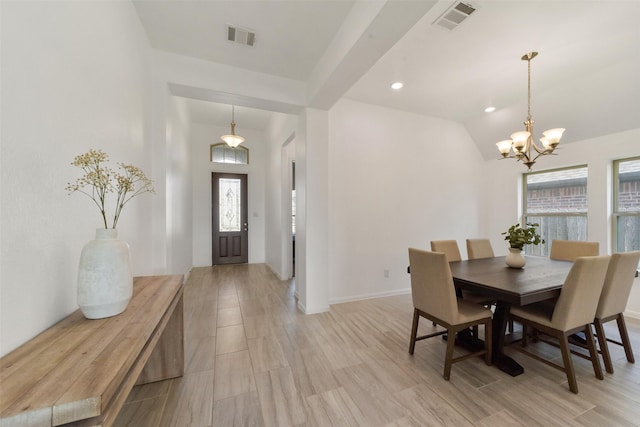 dining room featuring light wood-type flooring, vaulted ceiling, a healthy amount of sunlight, and a notable chandelier